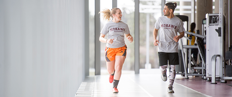 Two students running in the David Braley Athletics and Recreation Centre