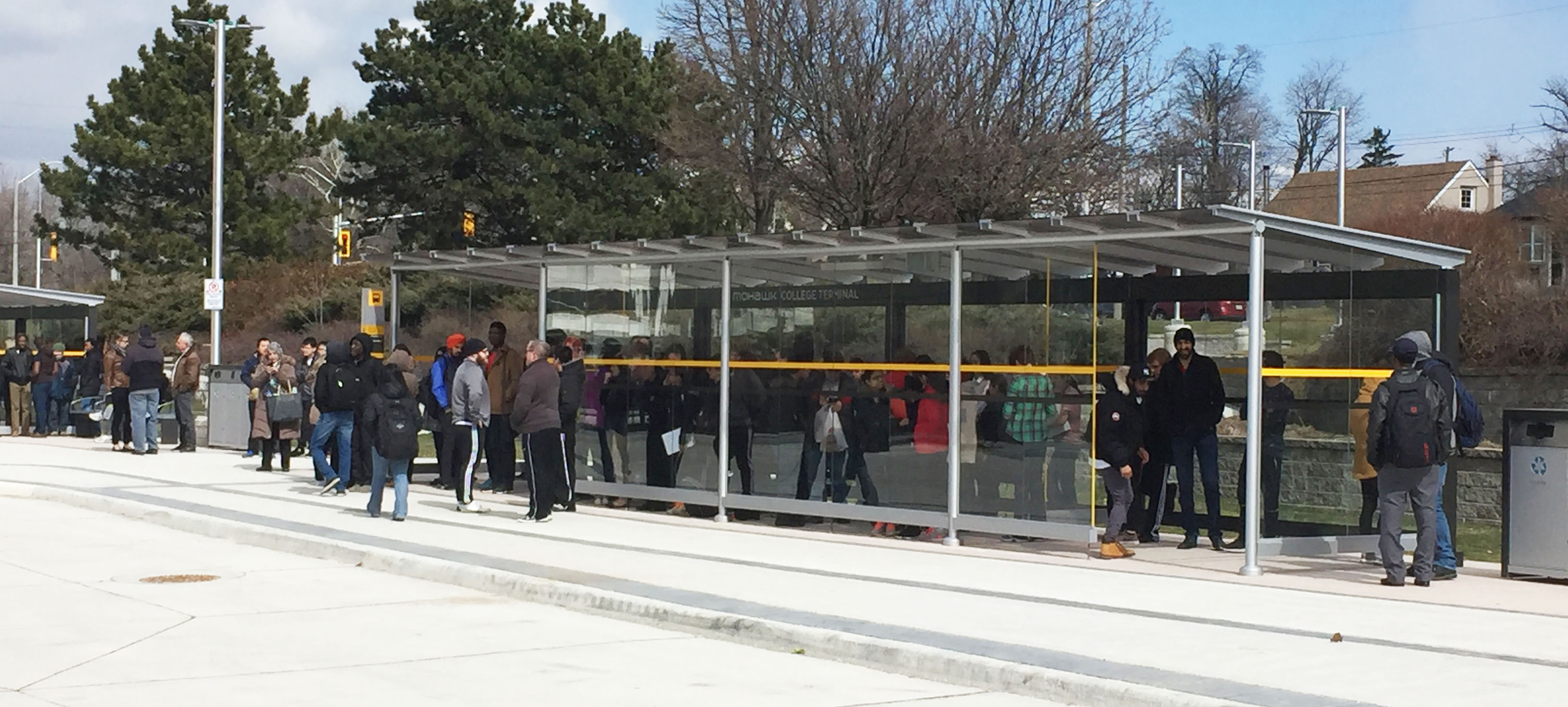 People standing under a transit terminal shelter