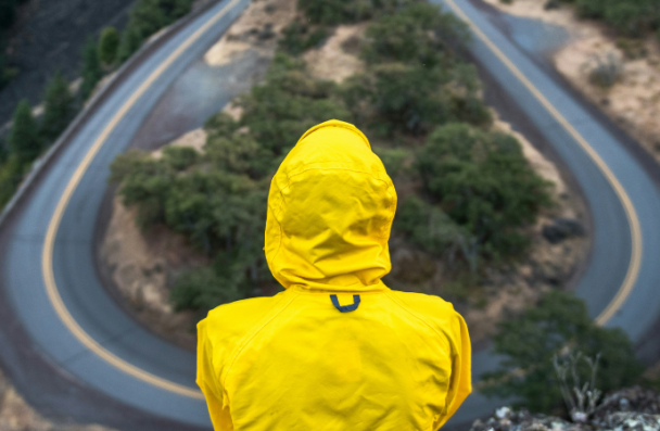 Image of a person sitting on a ledge looking over a winding road