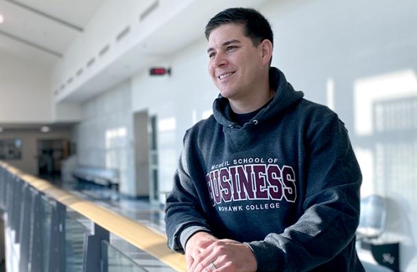 Mike wearing a Business Mohawk College sweater looking over a railing in the I-wing at Mohawk College.