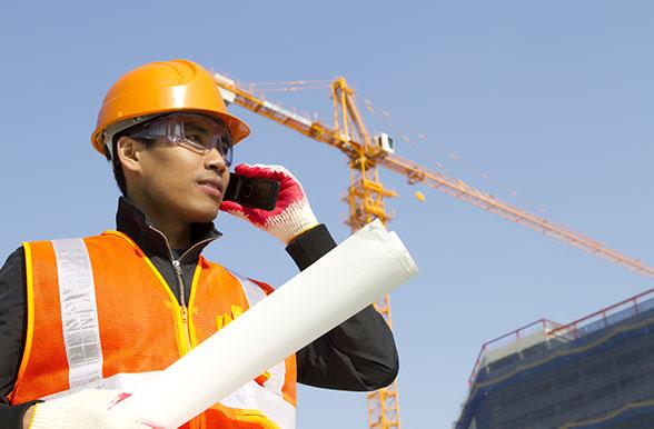 Civil Engineering Technician student on the phone with a crane in the background.