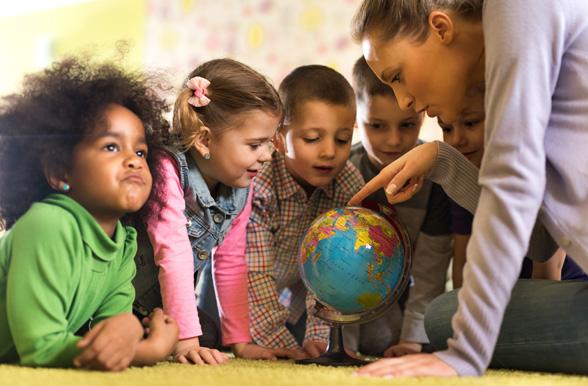 group of children at preschool examining world globe with their teacher