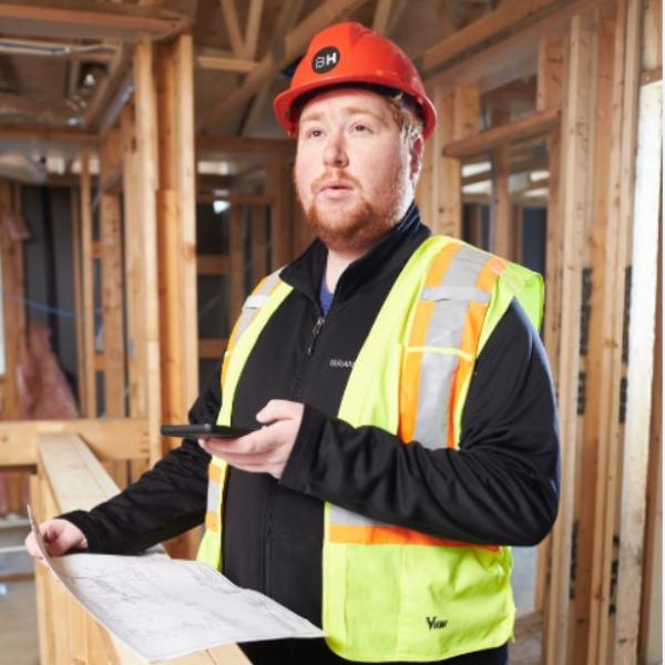 Man ponders construction blueprints in partially built home.