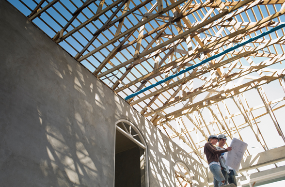Two engineering technicians reviewing plans inside a building under construction.
