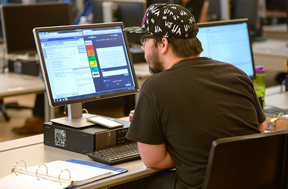 a mohawk college student writing code on computer