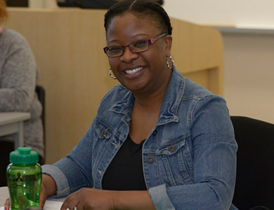 Academic Upgrading student in class, smiling for the photo.