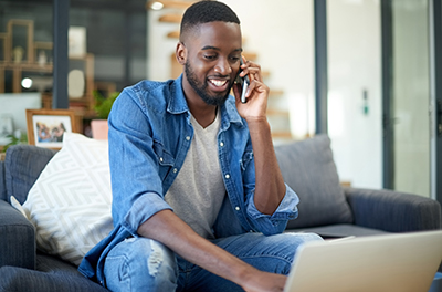 Man working on a computer while talking on a phone