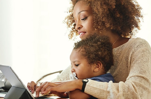woman looking something up on a tablet with a small child in her lap