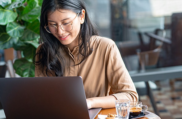 a woman with glasses working at a laptop