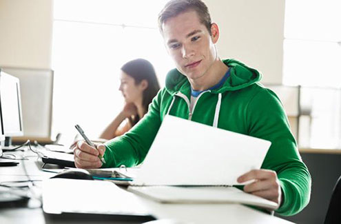 a young man working at a computer with a notebook