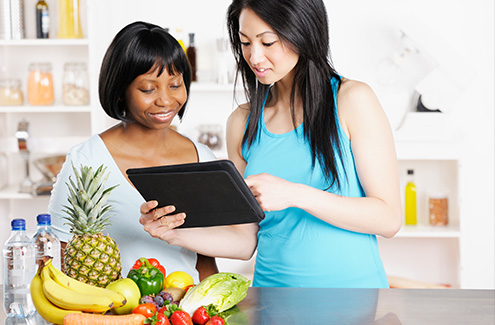 two people with a tablet and some healthy fruit