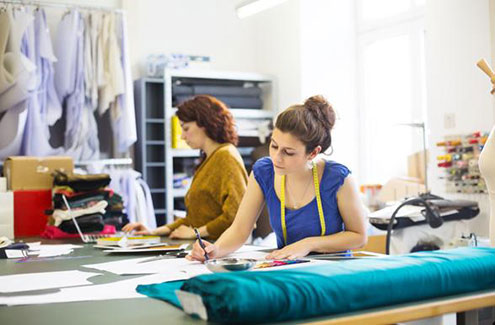 two people in a dressmaking studio with fabric