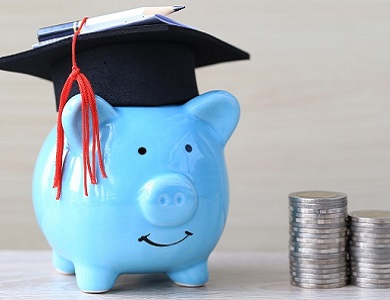 a piggy bank wearing a graduation cap with coins beside it
