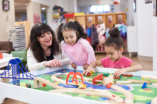 Childhood educator in the classroom with kids playing