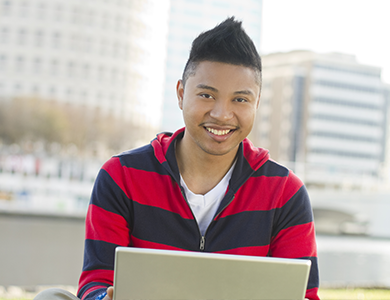 International Student working with a laptop and smiling