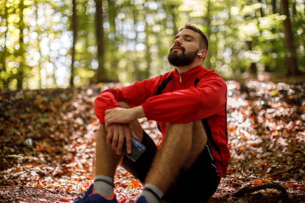 Young bearded Middle Eastern man meditating in a sun-dappled forest.