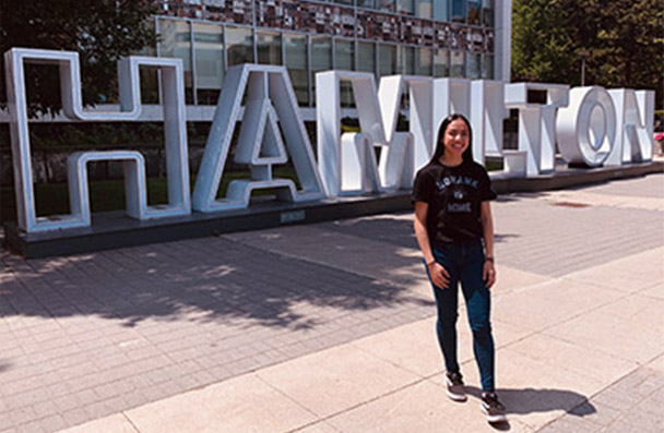 Student infront of the Hamilton sign