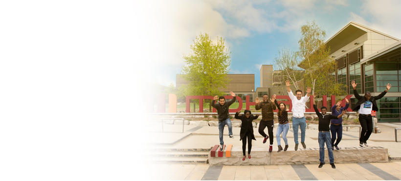 Mohawk students jumping in front of Mohawk sign