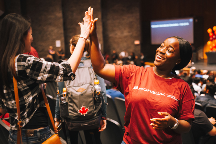 A volunteer greets an orientation attendee with a high five