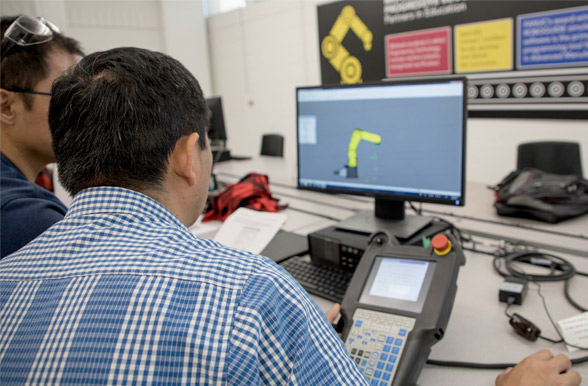 mechatronic system students viewing digital robot arm on computer