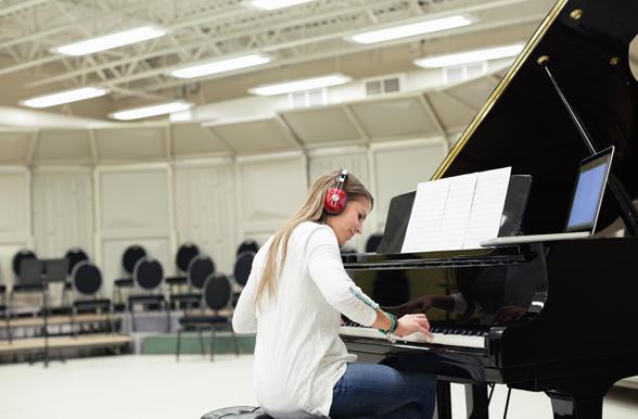 Student wearing headphones playing a grand piano