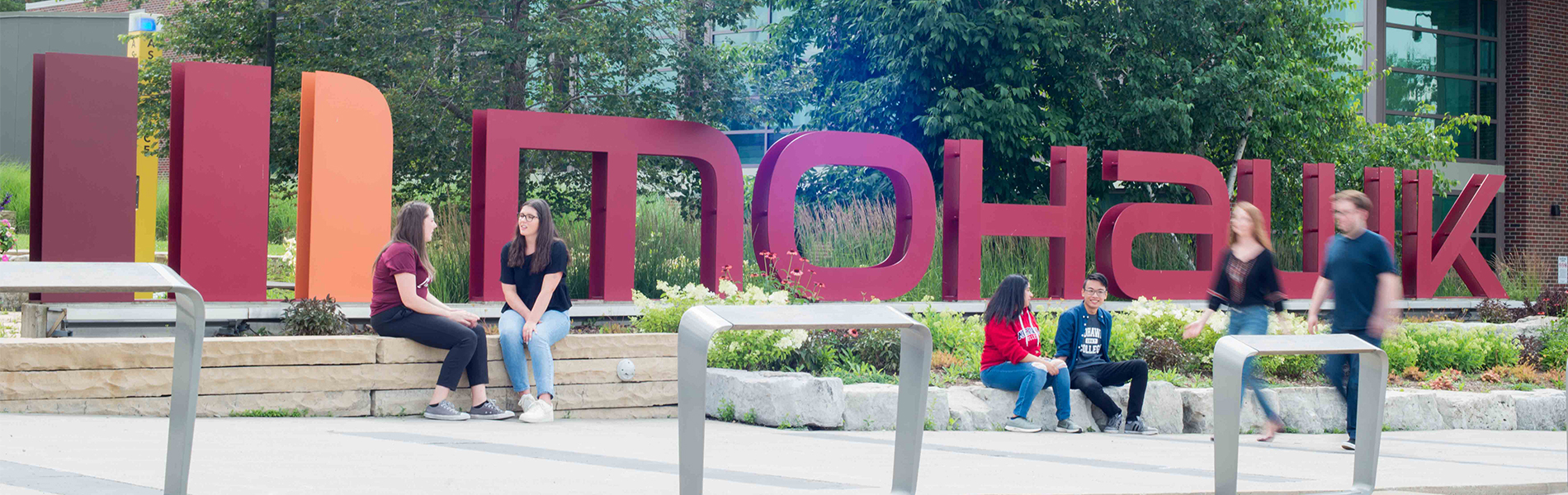 students sitting outside near the Mohawk sign