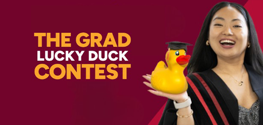 student holding a rubber duck with a graduation cap on its head