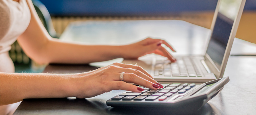 person on computer and calculator