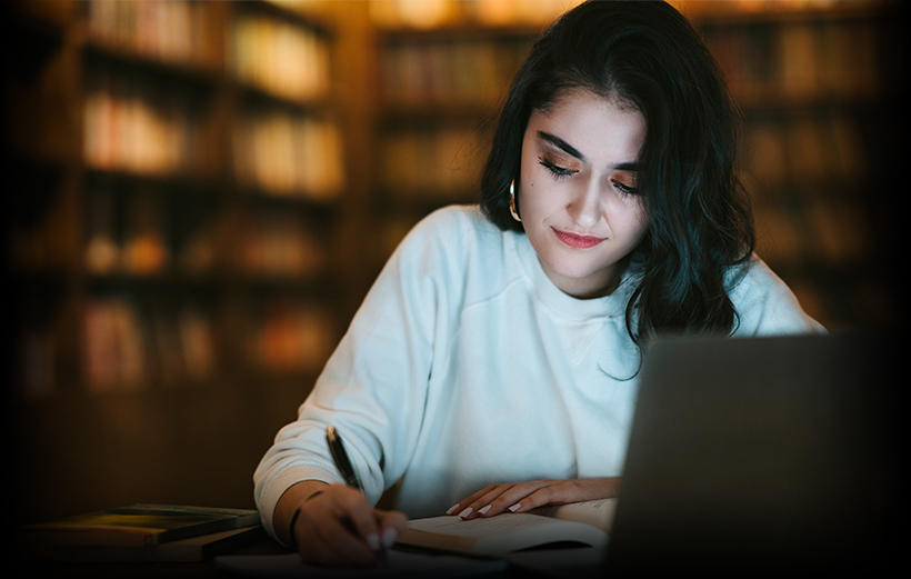 Student writing and using a laptop