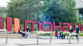 Students on outside in front of the Mohawk College sign.