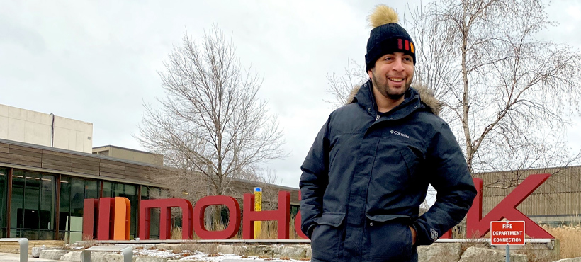 Student wearing Mohawk clothing in front of the Mohawk sign at Fennell Campus