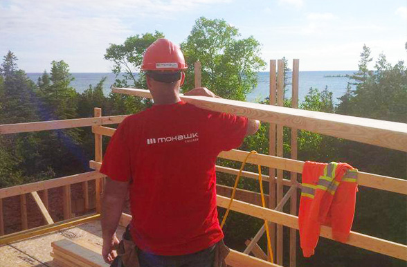 Mohawk College construction student carrying lumber at a job site.