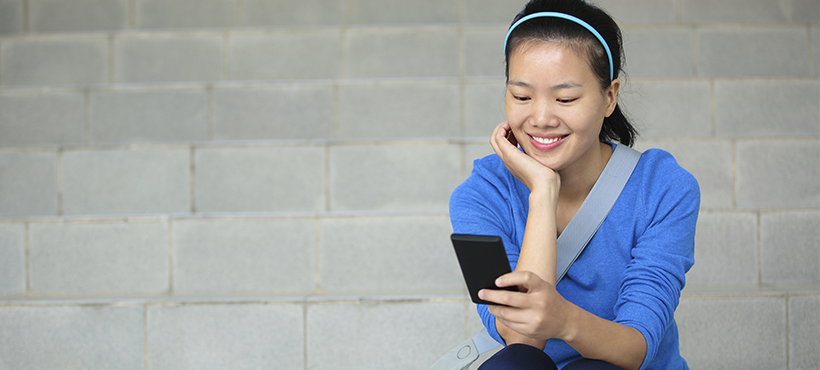 Student using cellphone while sitting on stairs.