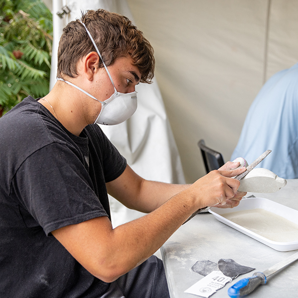 Ethan using a file on a soapstone sculpture.