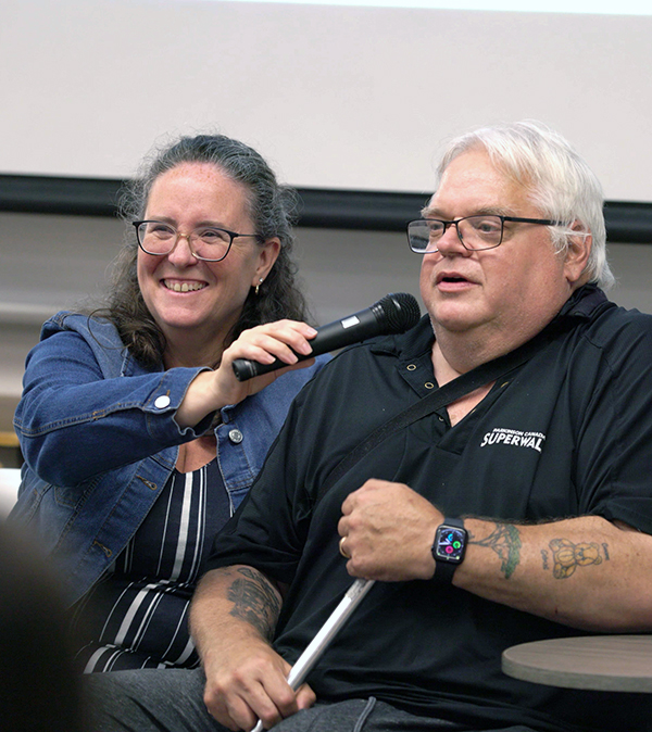 A patient partner speaking into a microphone held by a facilitator.