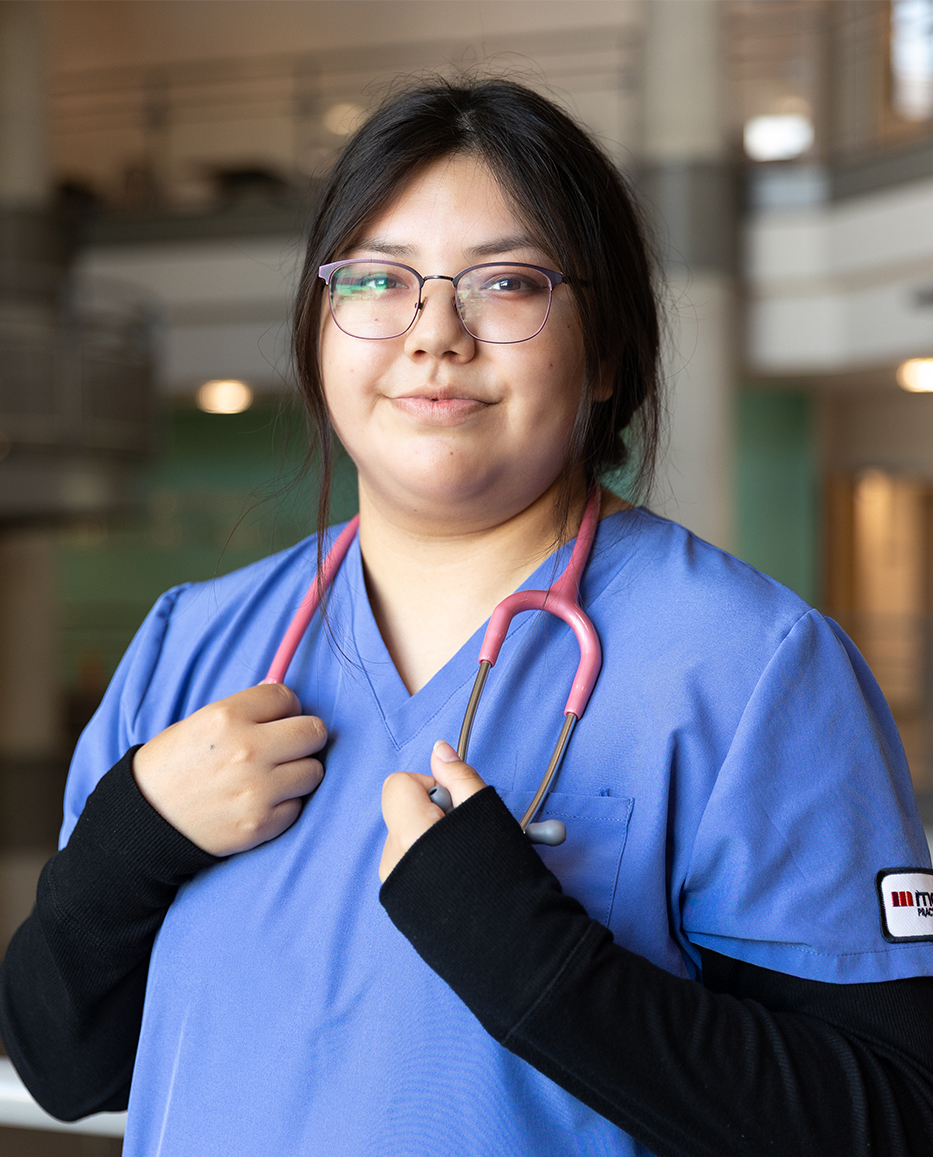 Brooke Meekis standing in the hallway of Mohawk College in scrubs