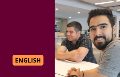 Two students sitting around a table. One of them is smiling lookins at the camera