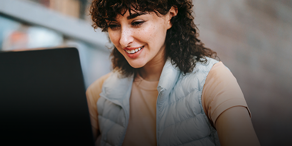 Person smiling while using a laptop