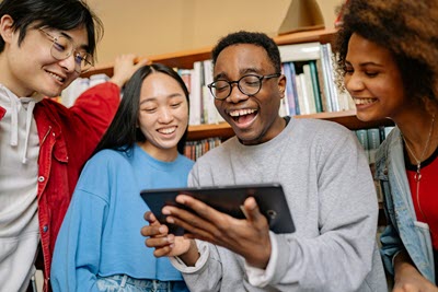 group of students looking at an ipad in the library