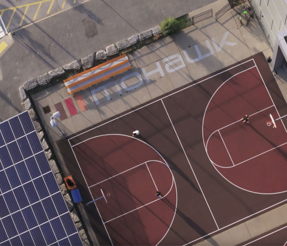 Overhead photograph of the Mohawk College logo on the ground next to a basketball court