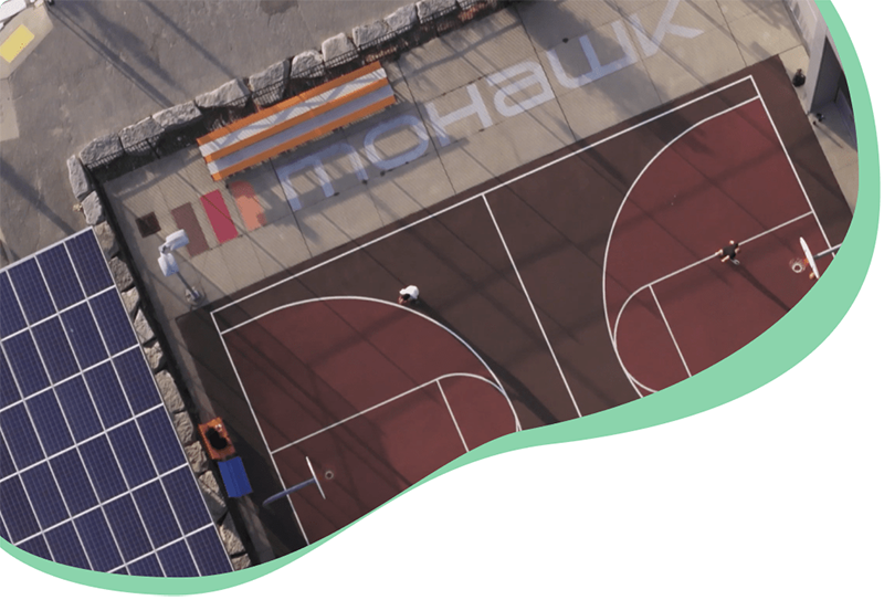 Overhead photograph of the Mohawk College logo on the ground next to a basketball court