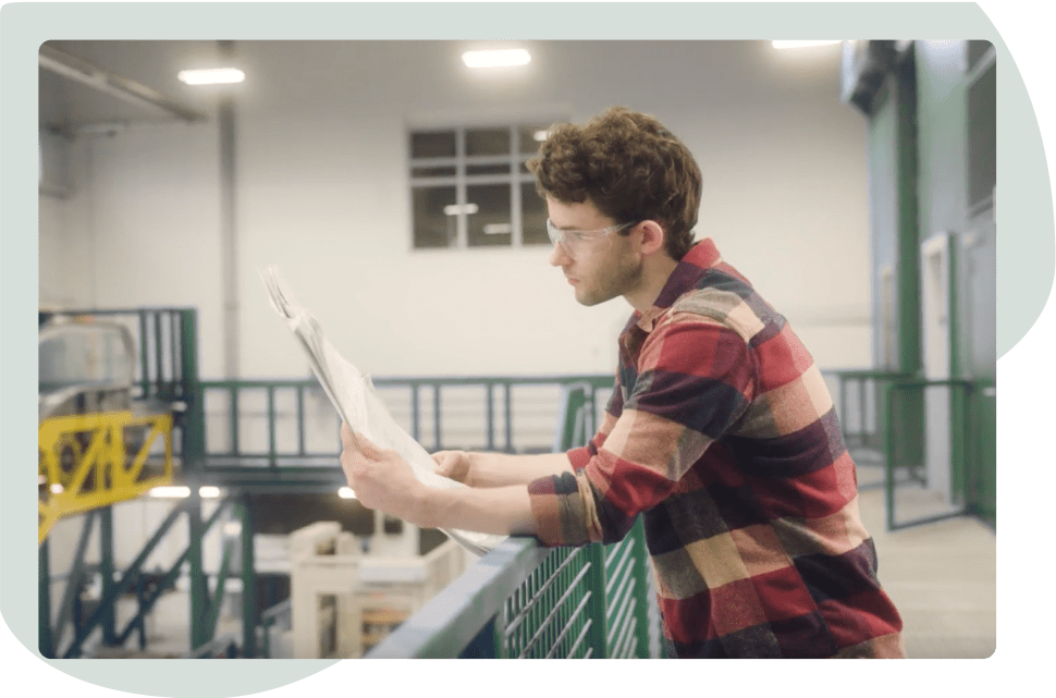 A person reading paperwork and looking over a warehouse