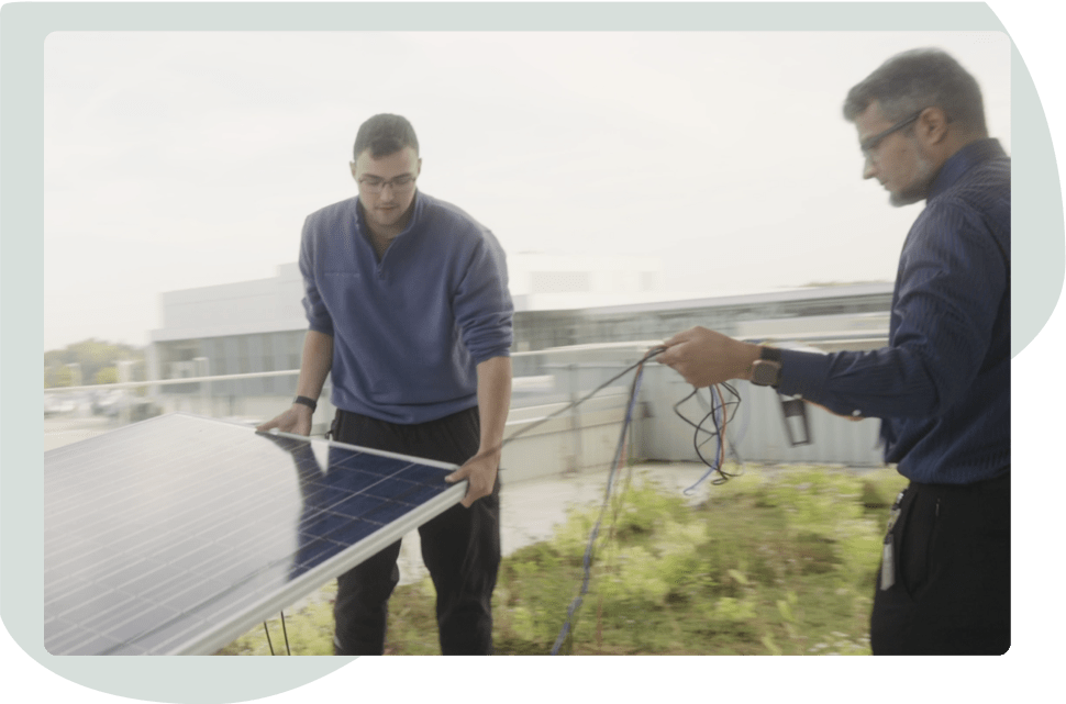 Two people working on setting up a solar panel outside