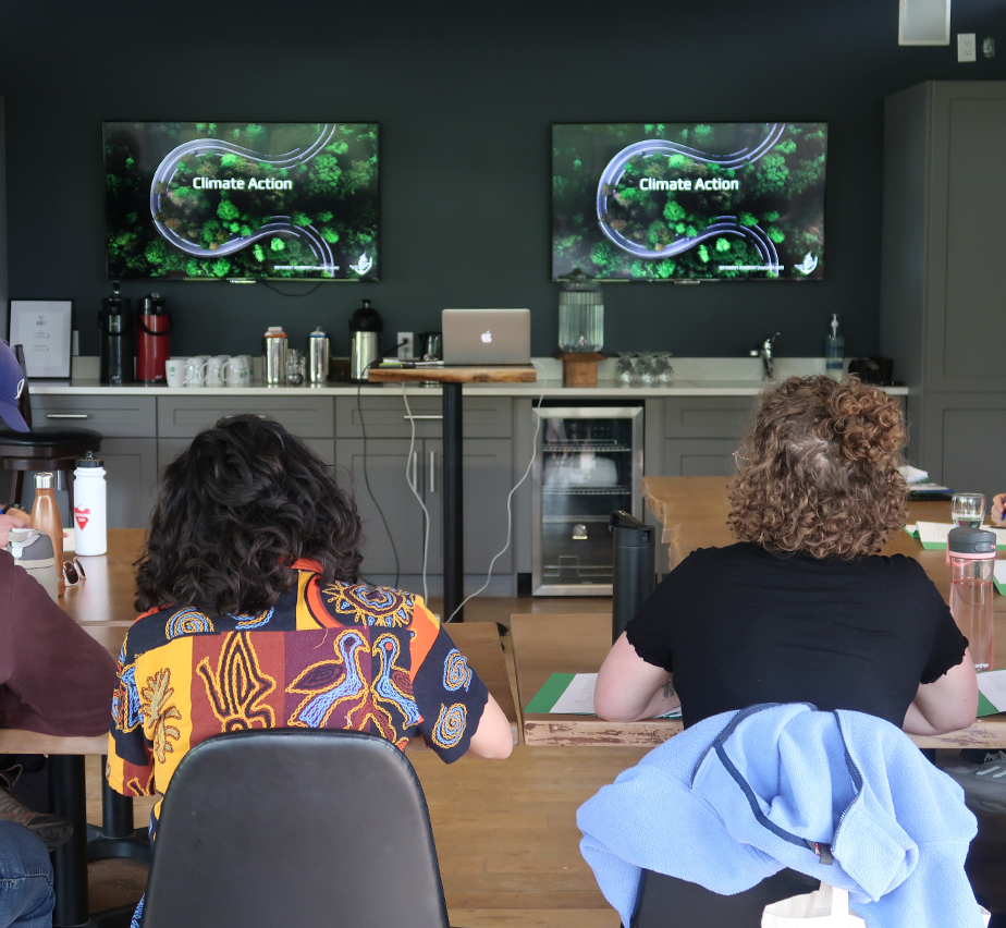 People sitting in a board room with books in front of them.