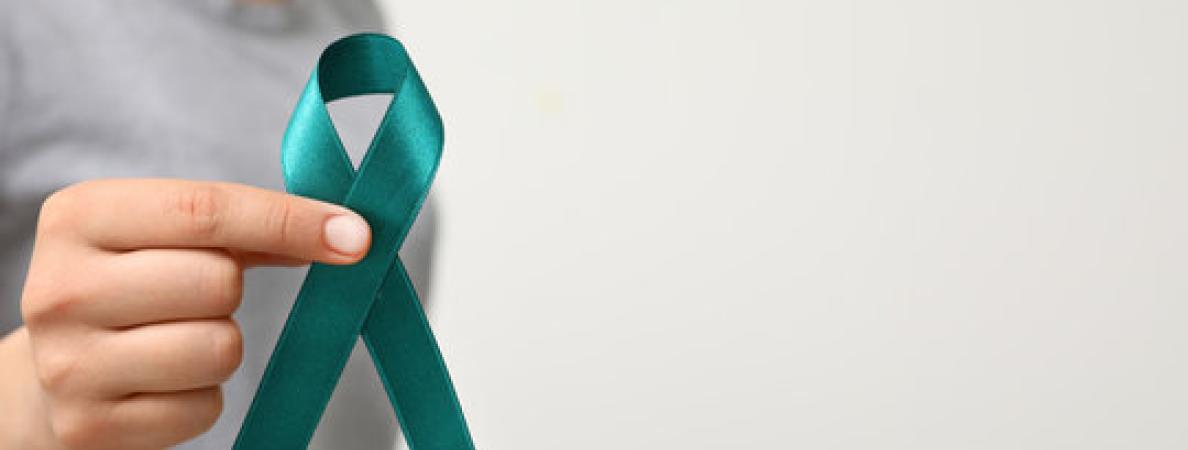 "Hand holding a teal ribbon"