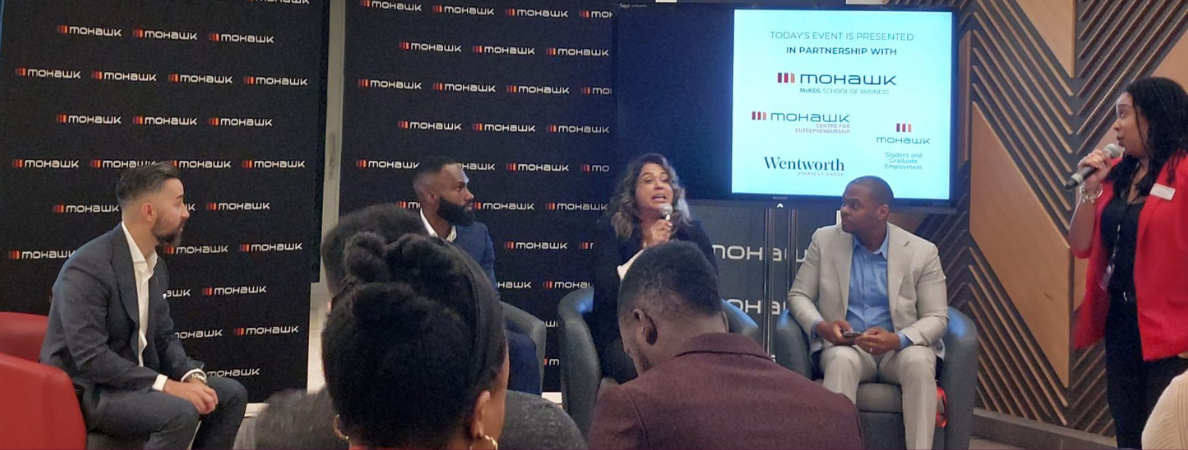 A panel of professionals sitting at the front of a room of spectators in a workshop