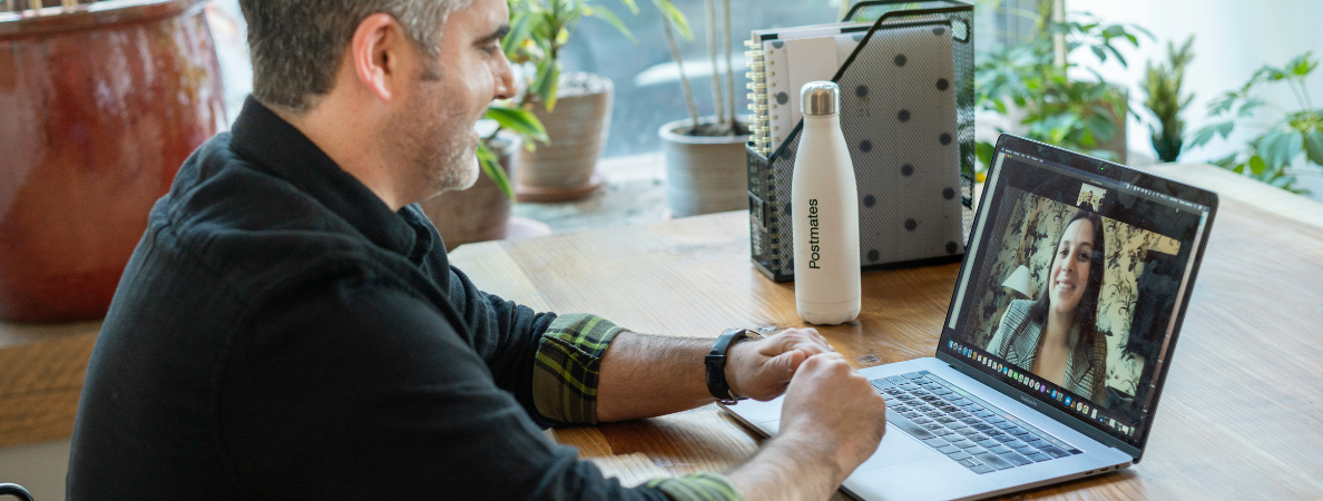 A man looking at a laptop with a video call in progress