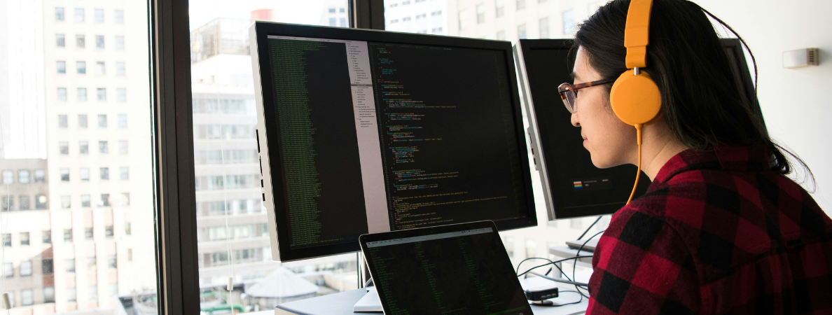 An image of a person working at a computer wearing headphones