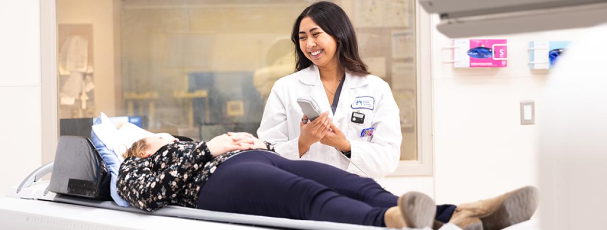 A tech talking with a patient on an MRI bed.