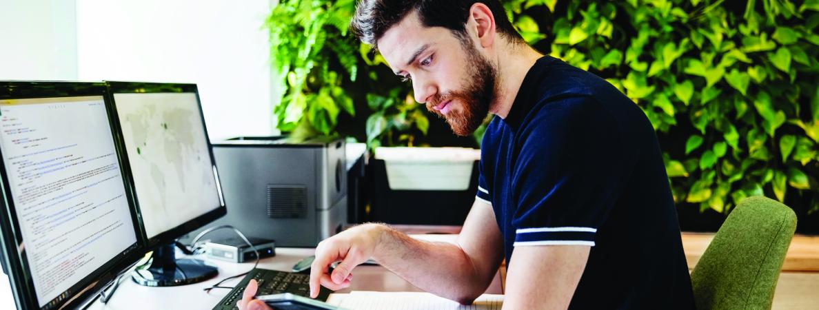Student in front of a computer and looking at a book.